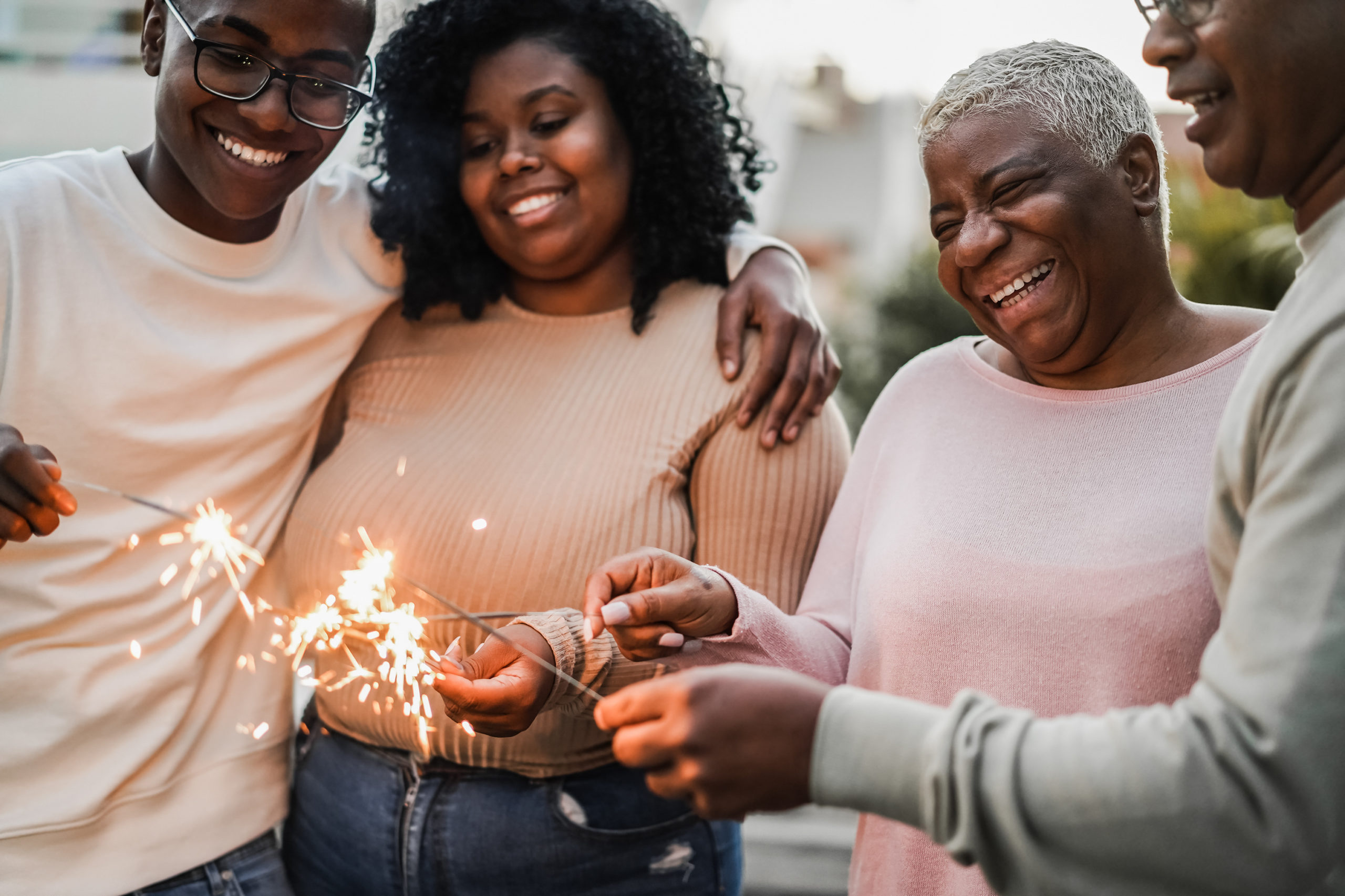 Happy black family celebrating with sparklers outdoor at home - Focus on mother face