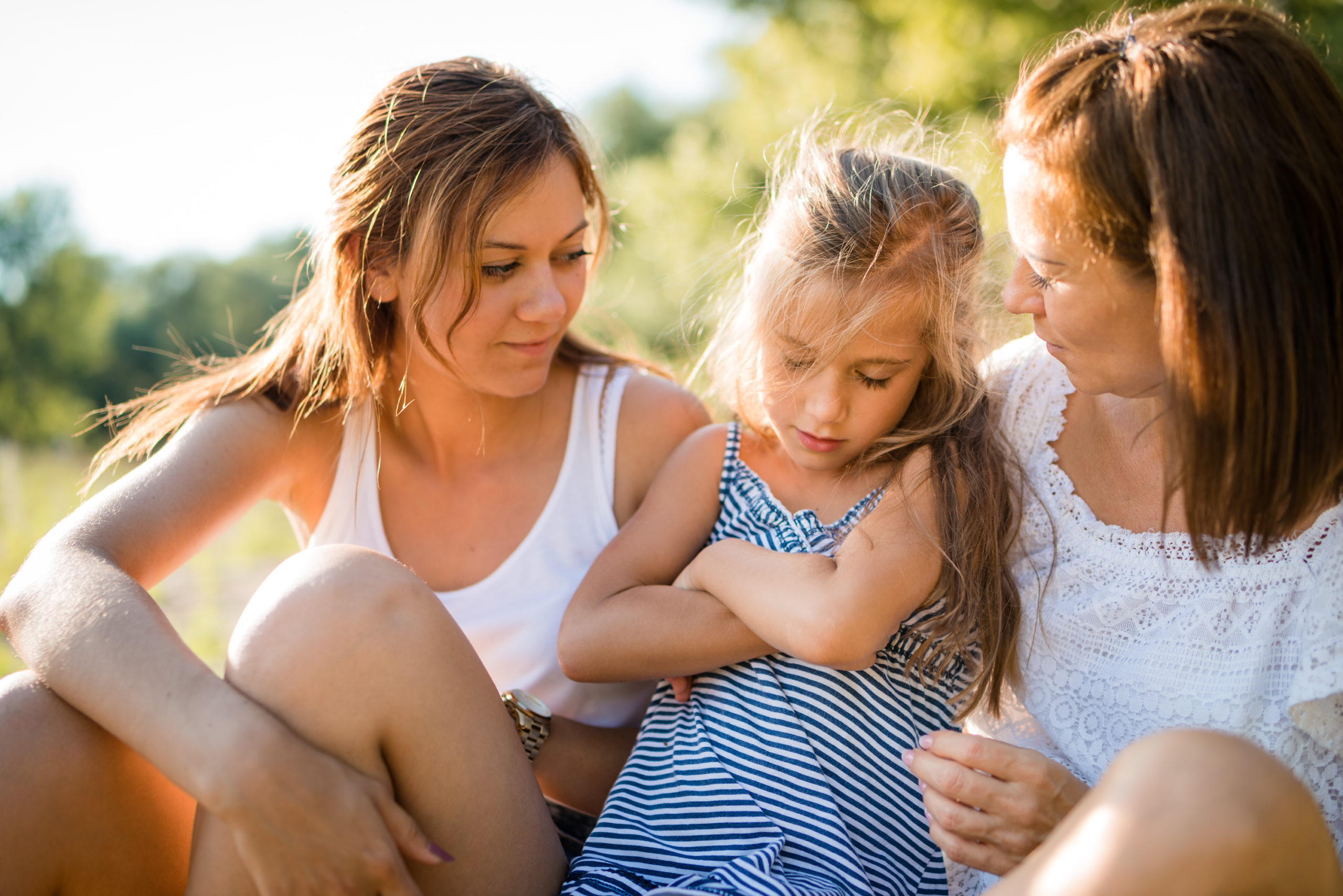Mother and adult daughter comforting young girl child Family consoling cute young little girl who is upset