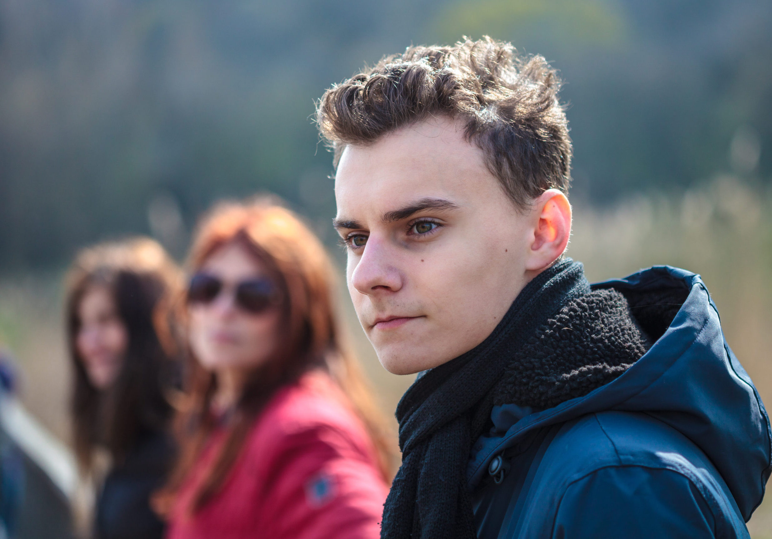 Closeup of a teenage boy with his family in the background